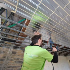 Installation d’un plafond chauffant-rafraîchissant dans un mas en rénovation, pose des plaques et des tubes par un installateur.