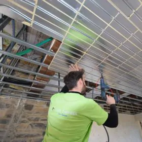 Installation d&rsquo;un plafond chauffant-rafra&icirc;chissant dans un mas en r&eacute;novation, pose des plaques et des tubes par un installateur.
